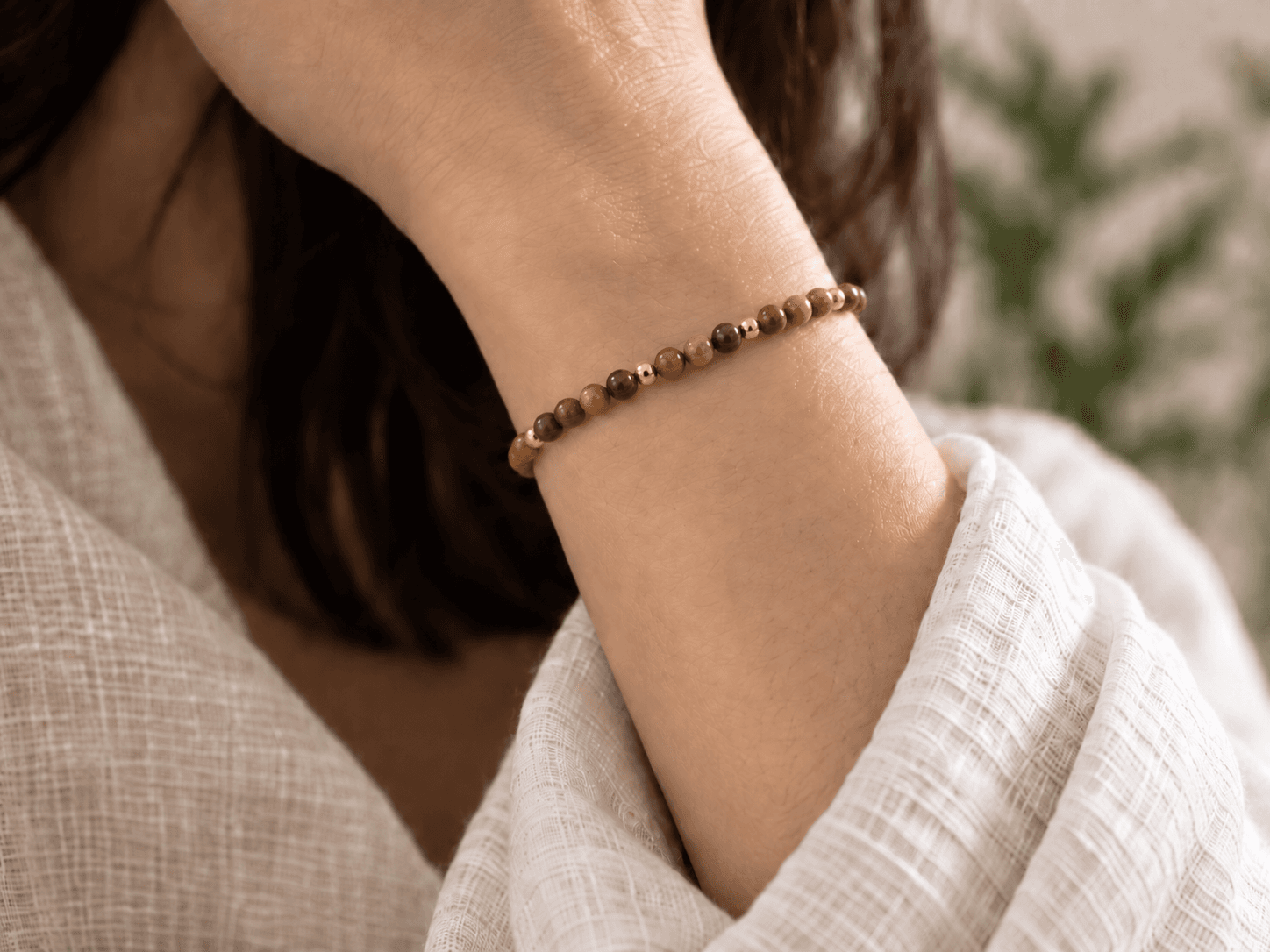 Earth bead bracelet in warm brown with small gold spacers, worn on a wrist, without a pendant