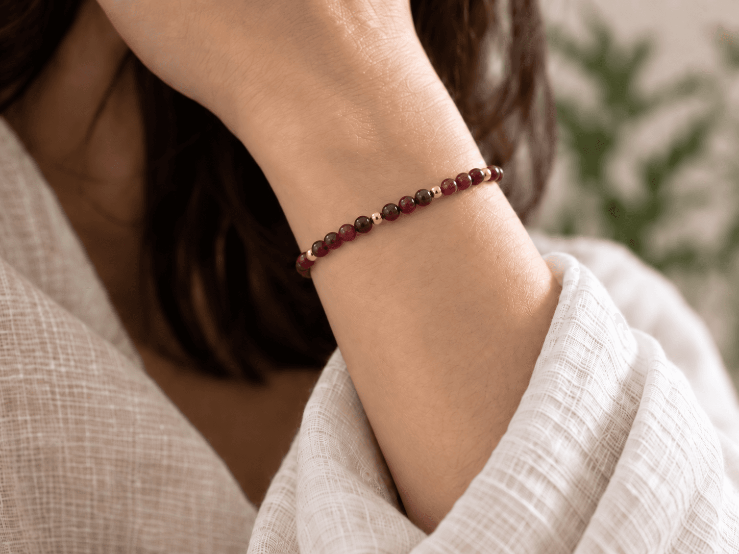 Fire bead bracelet in wine red with small gold spacers, worn on a wrist, without a pendant