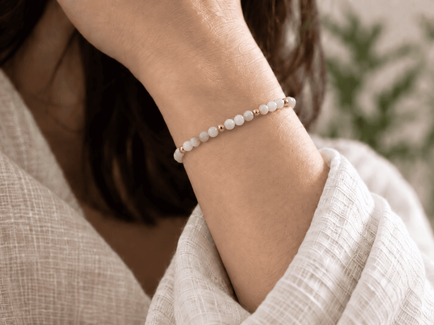 Metal bead bracelet in milky ivory with small gold spacers, worn on a wrist, without a pendant