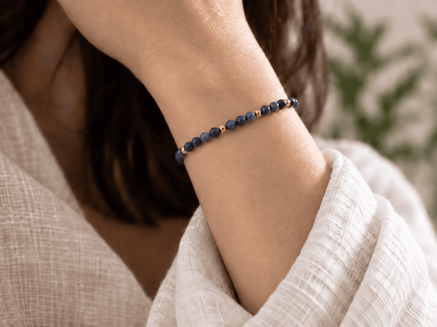 Water bead bracelet in midnight blue with small gold spacers, worn on a wrist, without a pendant