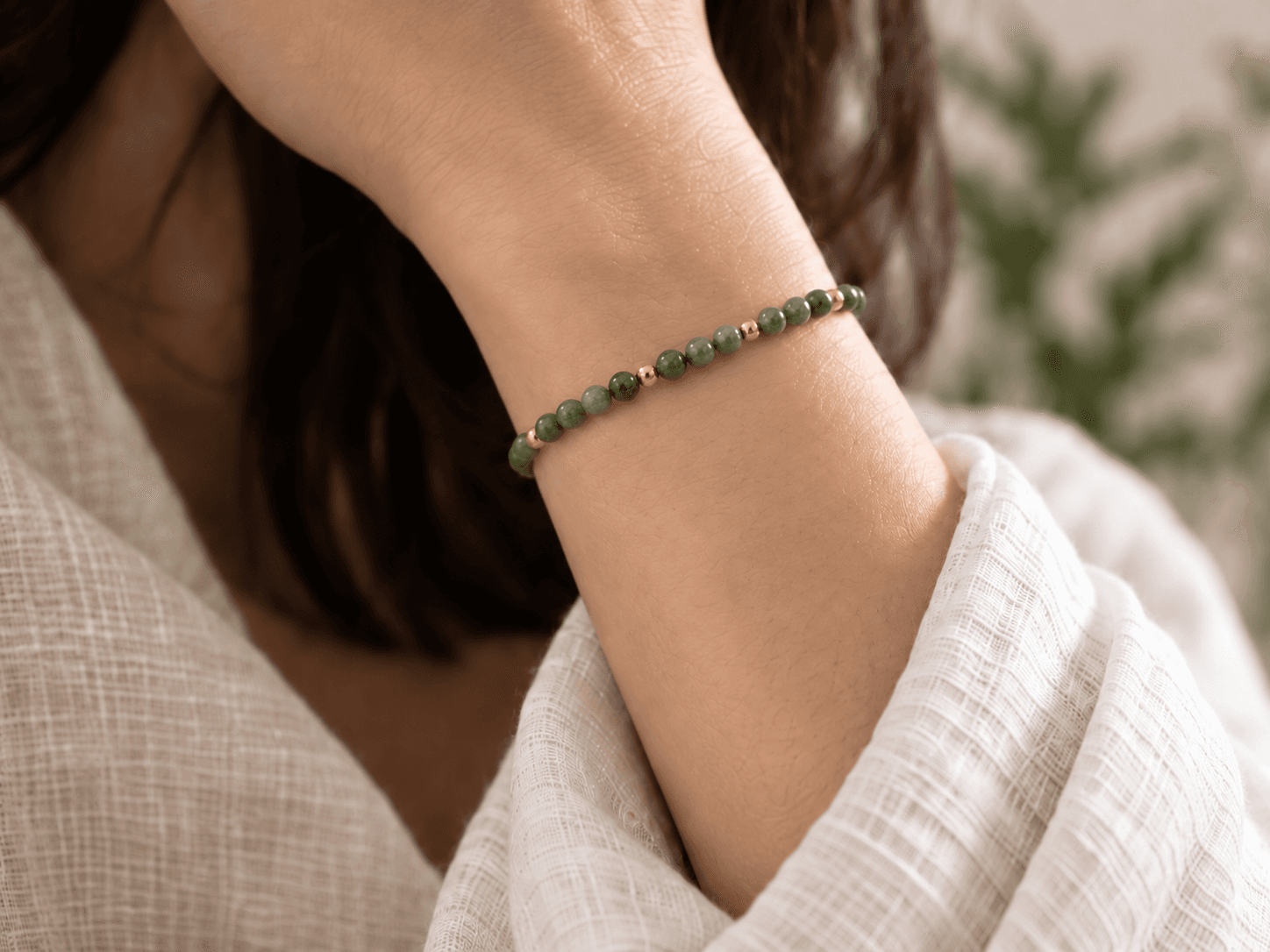 Wood bead bracelet in moss green with small gold spacers, worn on a wrist, without a pendant