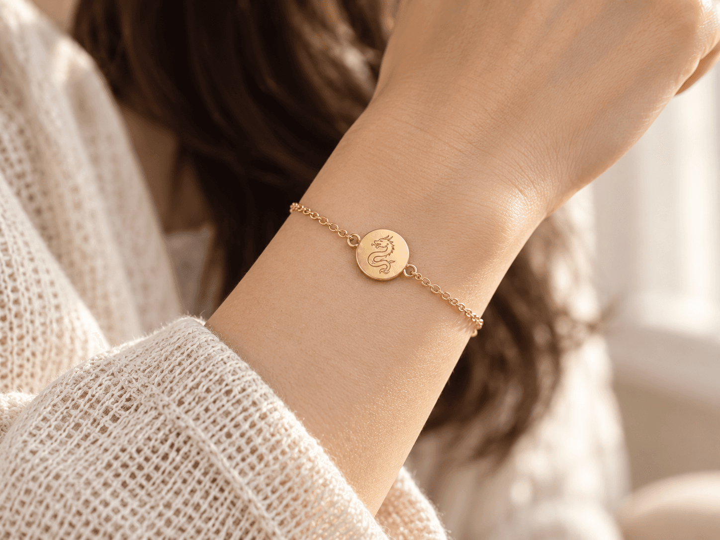 Concept image of a woman wearing a fine gold chain bracelet with an engraved Dragon medallion