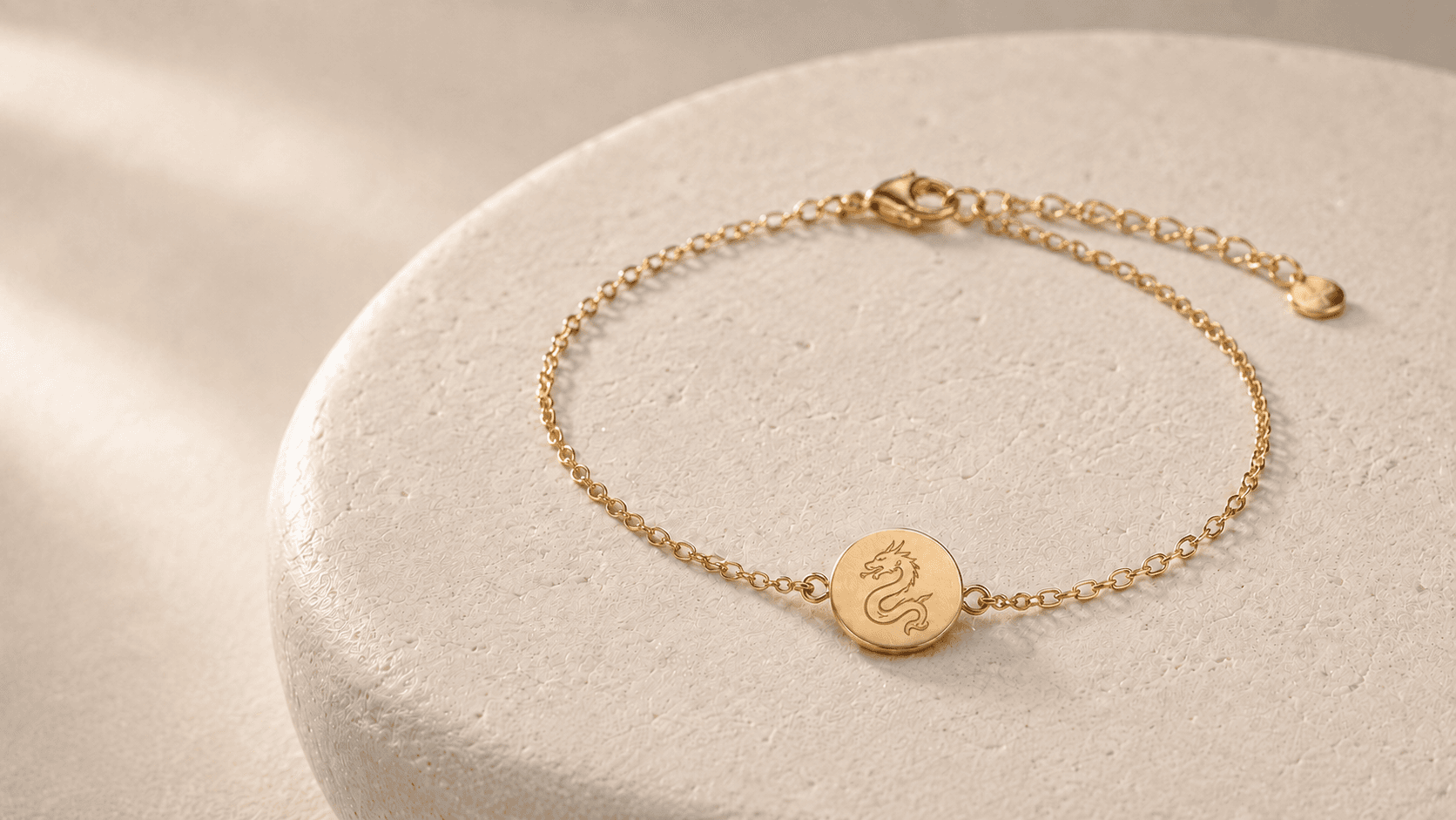Design concept of a complete gold-tone Dragon zodiac chain bracelet with engraved medallion, clasp and extension chain on pale stone