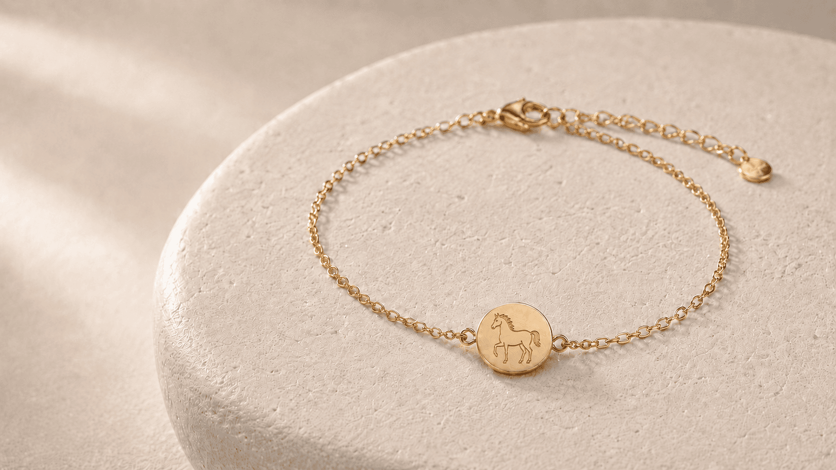 Design concept of a complete gold-tone Horse zodiac chain bracelet with engraved medallion, clasp and extension chain on pale stone