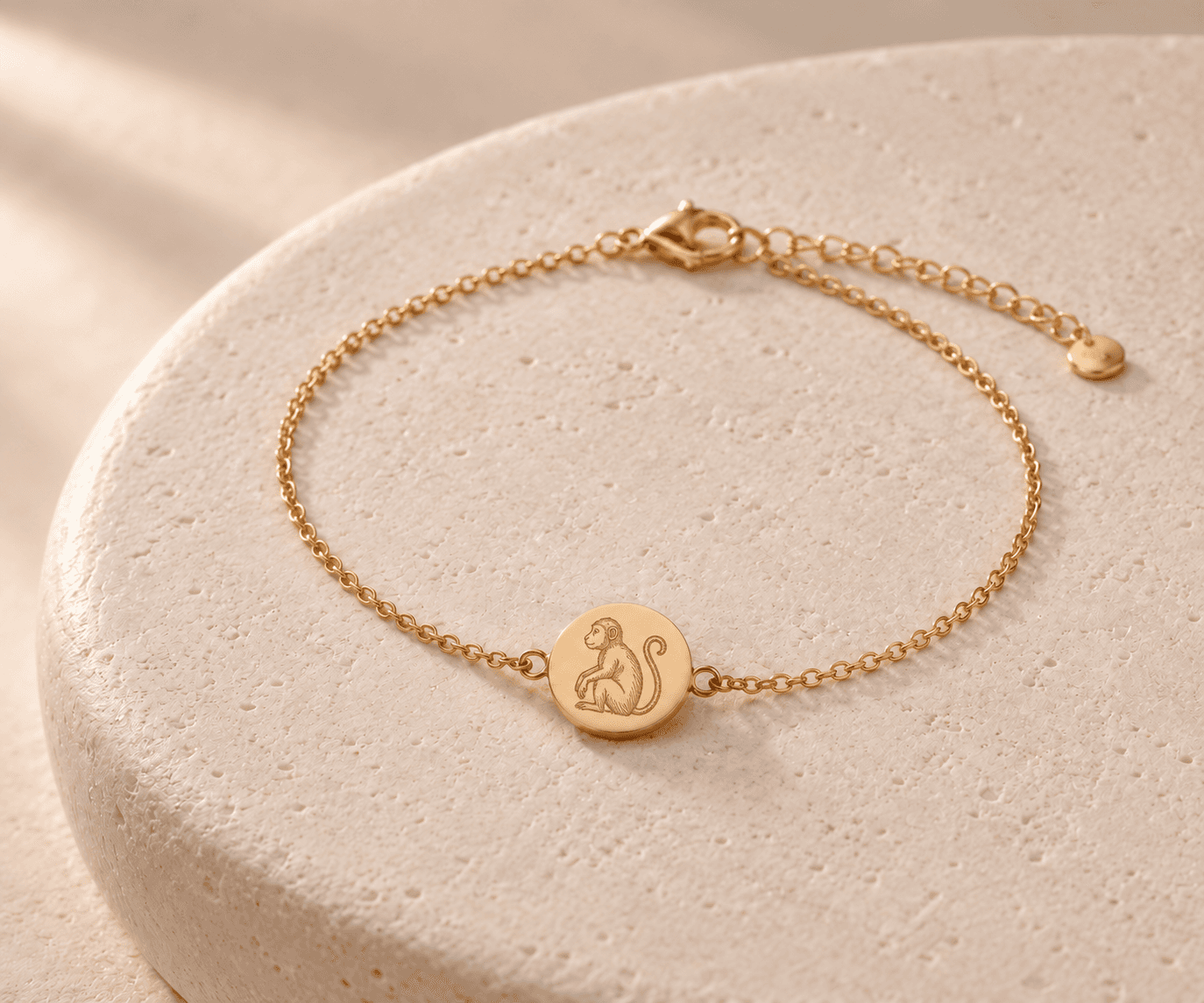 Monkey zodiac gold-tone chain bracelet design concept on an ivory stone platform