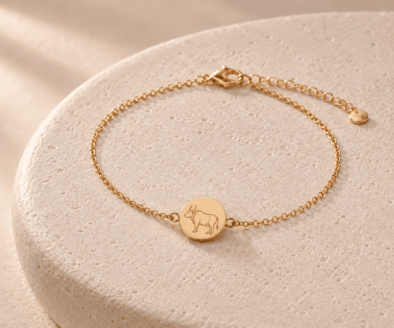 Ox zodiac gold-tone chain bracelet design concept on an ivory stone platform