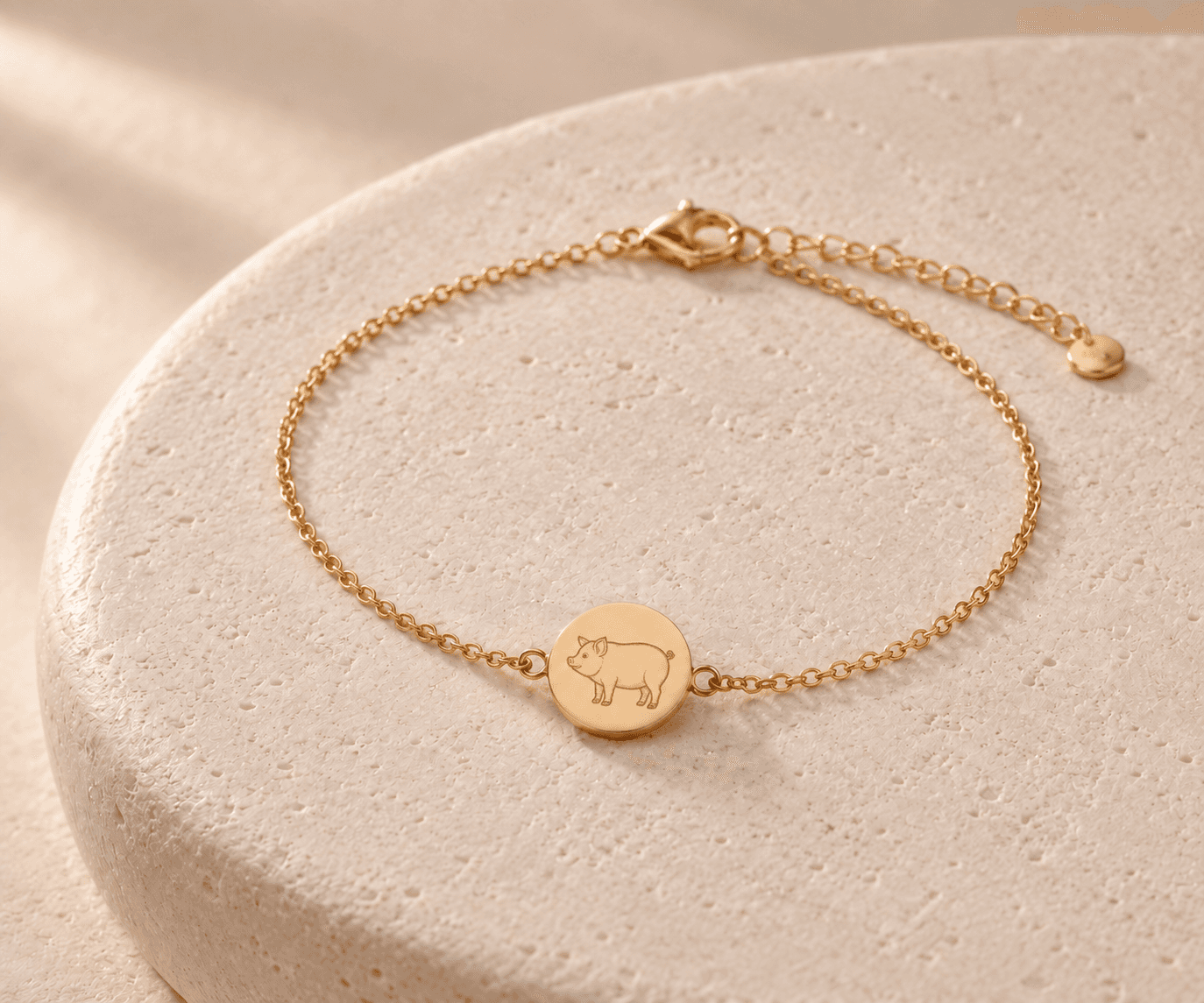 Pig zodiac gold-tone chain bracelet design concept on an ivory stone platform